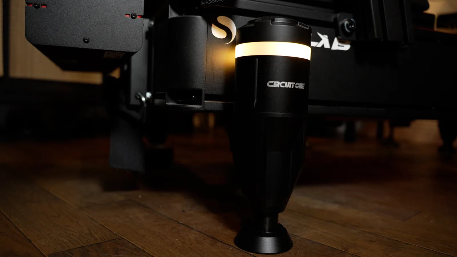 A D Force 1 actuator lit amber under the corner of a Sim-Lab rig on a wooden floor